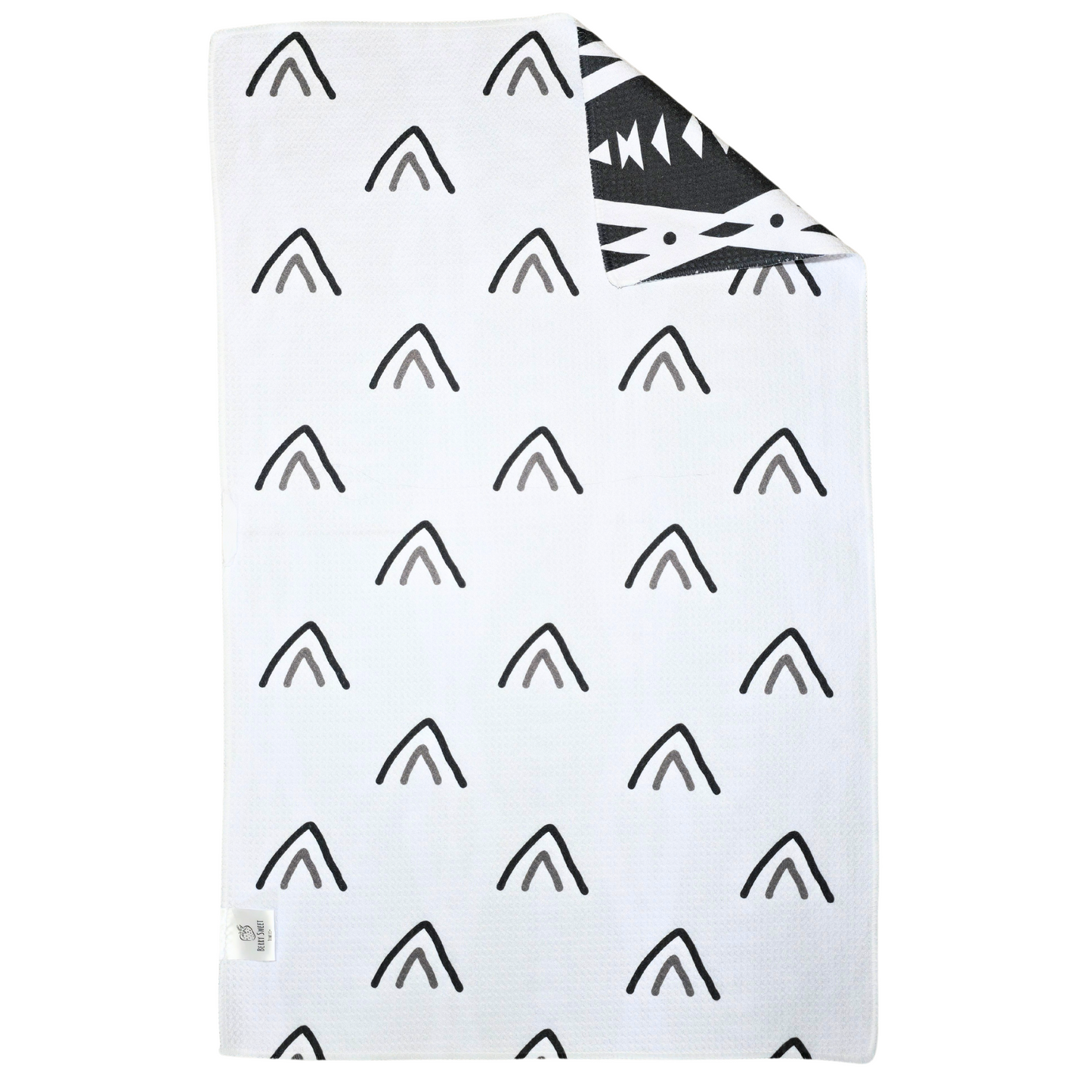 Reverse side of a double-sided waffle weave microfiber hand towel with a white background and scattered black and gray arrow-style triangle designs, with a folded corner showing the black geometric patterned front.