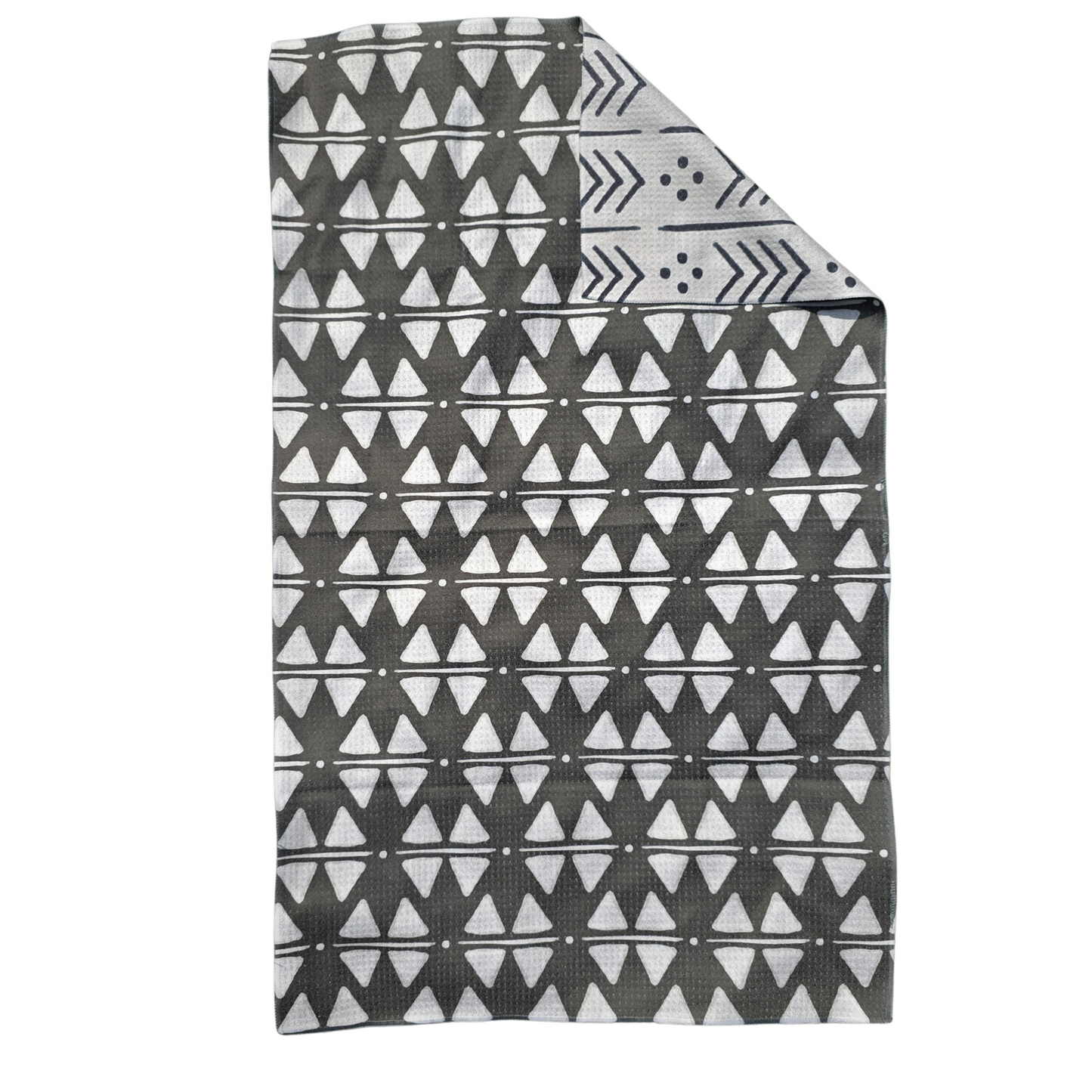Full view of a single microfiber towel with a corner folded over to reveal the reverse side. The front is black with white triangle, dot and line patterns, while the flipped corner shows the cream underside with black arrow, line and dot designs.