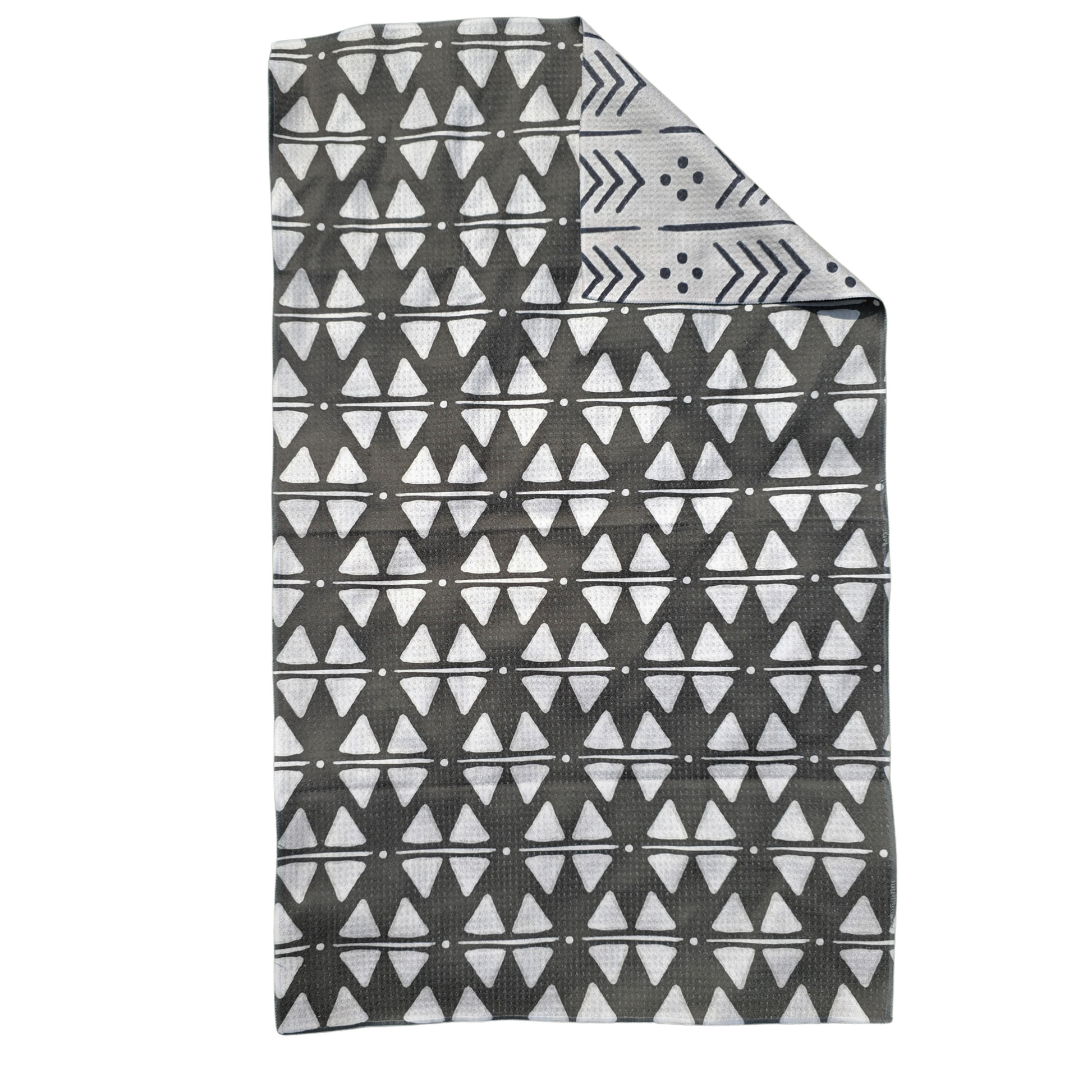 Full view of a single microfiber towel with a corner folded over to reveal the reverse side. The front is black with white triangle, dot and line patterns, while the flipped corner shows the cream underside with black arrow, line and dot designs.