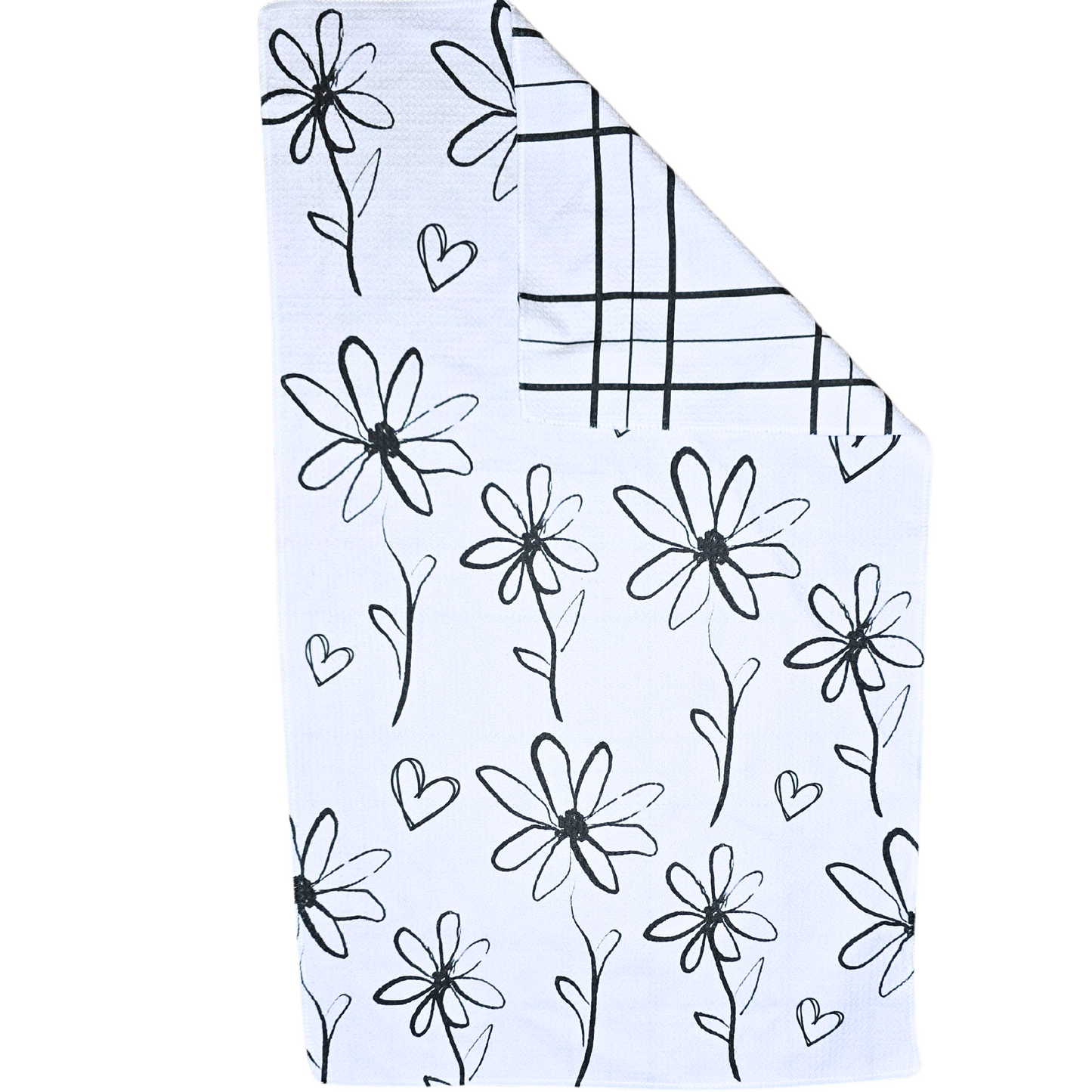Double-sided waffle weave microfiber hand towel laid flat, featuring a white background with black hand-drawn flowers and small heart details, with a folded corner revealing the black grid patterned reverse side.