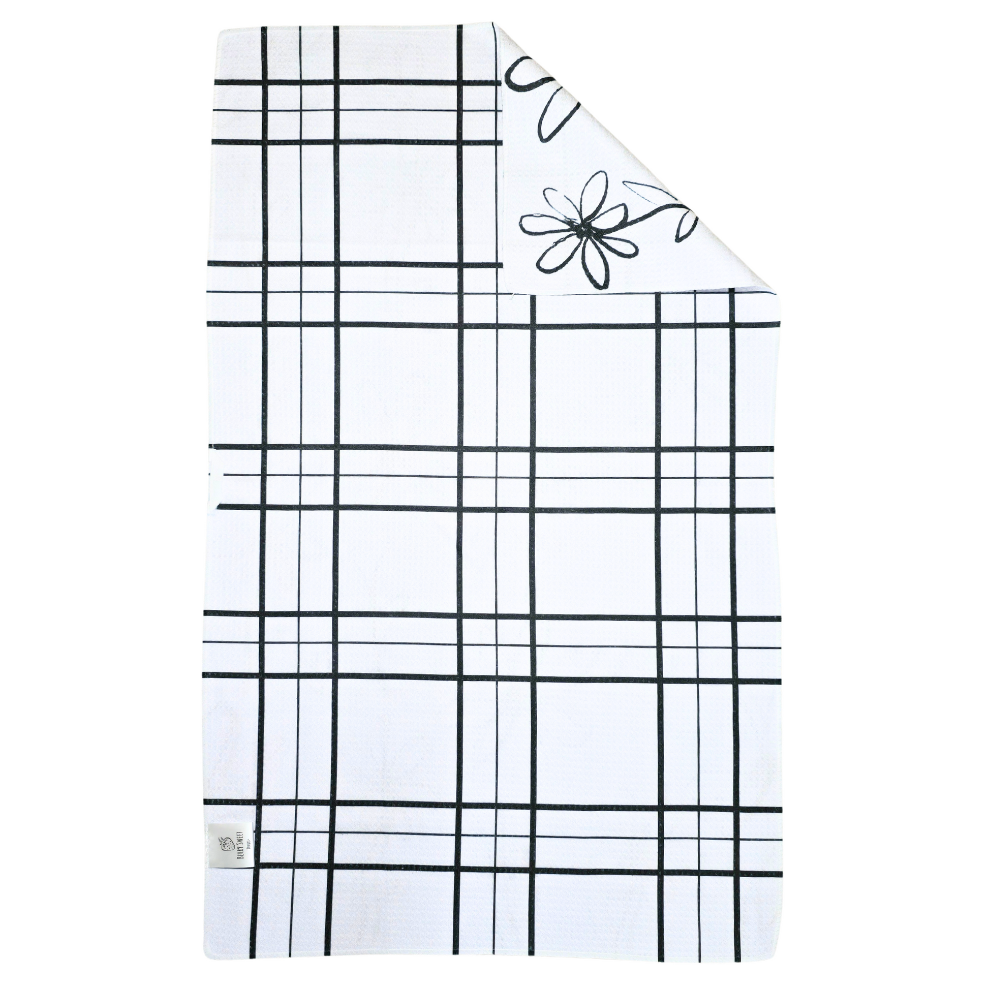 Reverse side of a double-sided waffle weave microfiber hand towel with a white background and black grid pattern, with a folded corner showing the white daisy and heart patterned front.