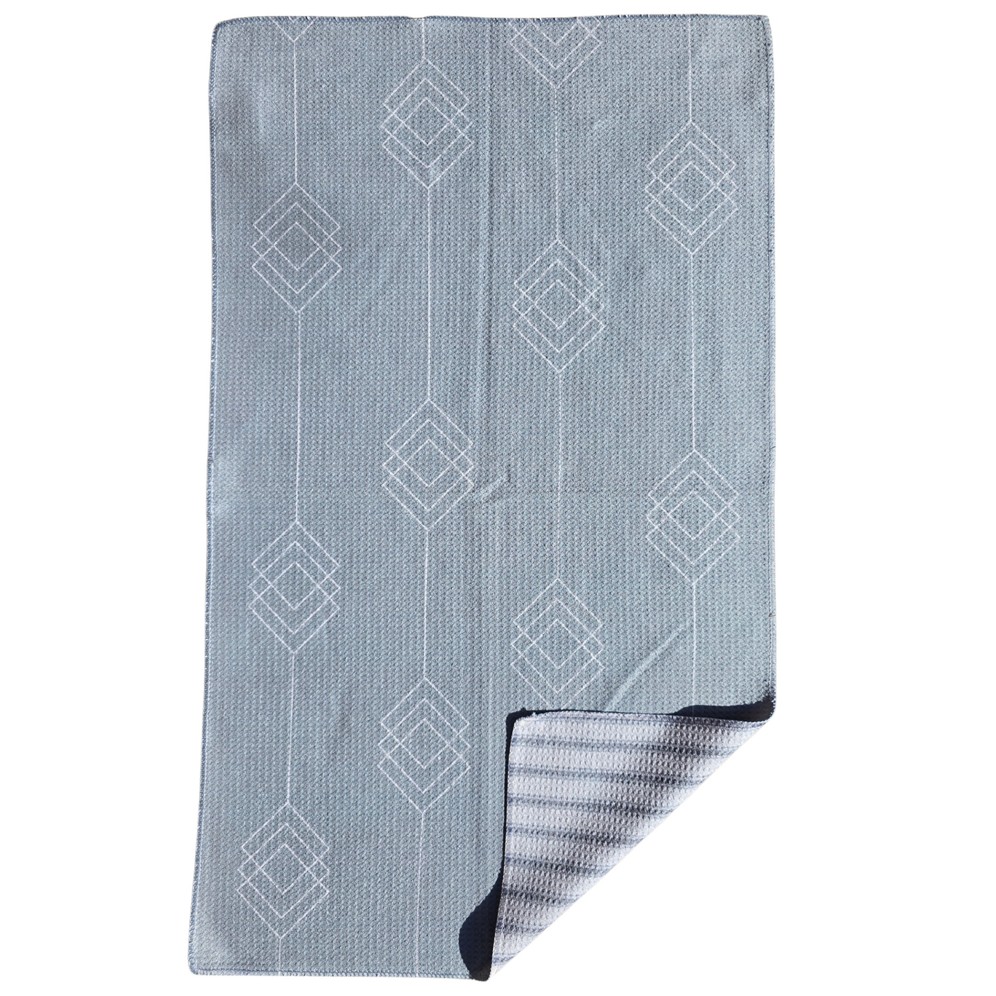 Full view of a waffle weave microfiber hand towel with light gray background and white geometric diamond patterned front, with a folded corner revealing the light and dark gray striped reverse side.