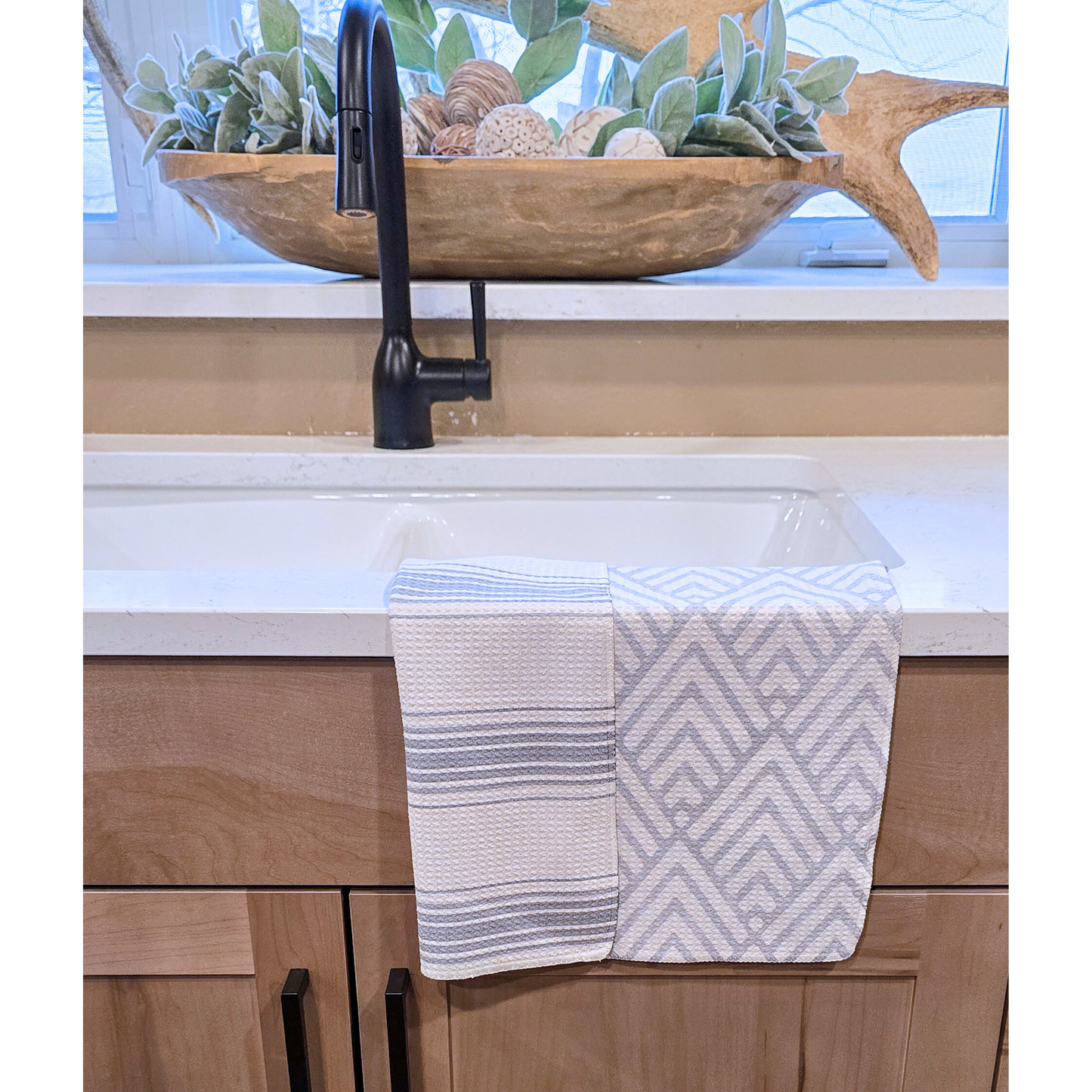 Single waffle weave microfiber hand towel folded over a kitchen sink, showing the front with a light gray geometric pattern on a white background and the reverse with a white and gray striped pattern.