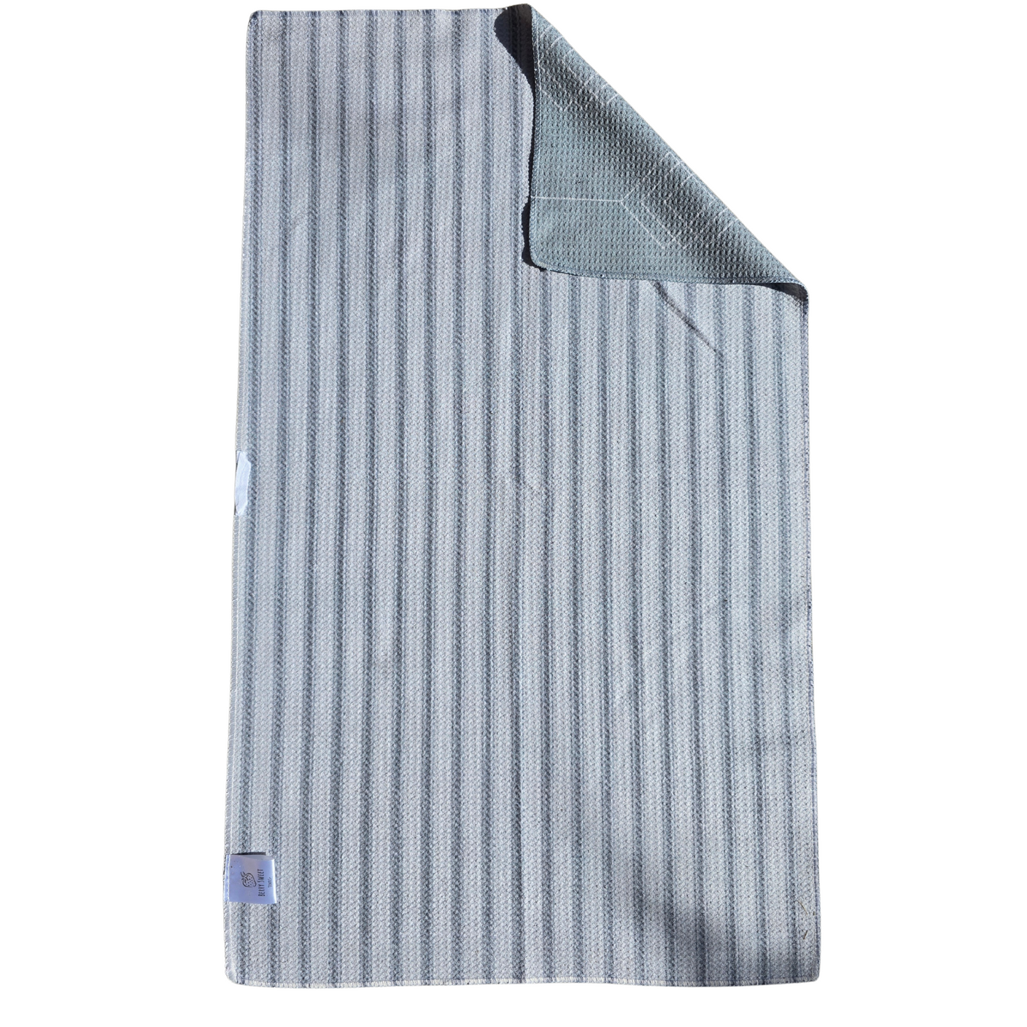 Full view of a waffle weave microfiber hand towel with light and dark gray striped pattern and folded corner revealing the light gray and  white geometric diamond patterned reverse side.