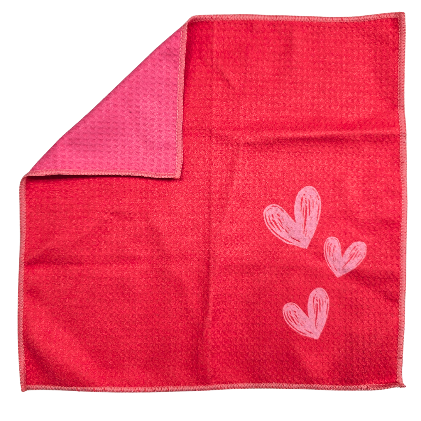 Double-sided waffle weave microfiber washcloth laid flat, featuring an orange-pink front with light pink heart design and a folded corner revealing the pink reverse side.