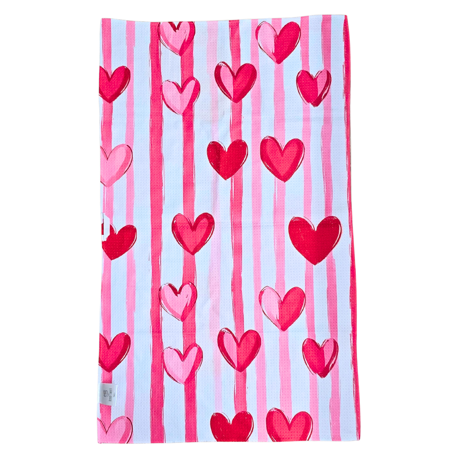 Full view of the reverse side of a waffle weave microfiber hand towel with vertical light pink, dark pink, and white stripes accented by red and pink heart designs.