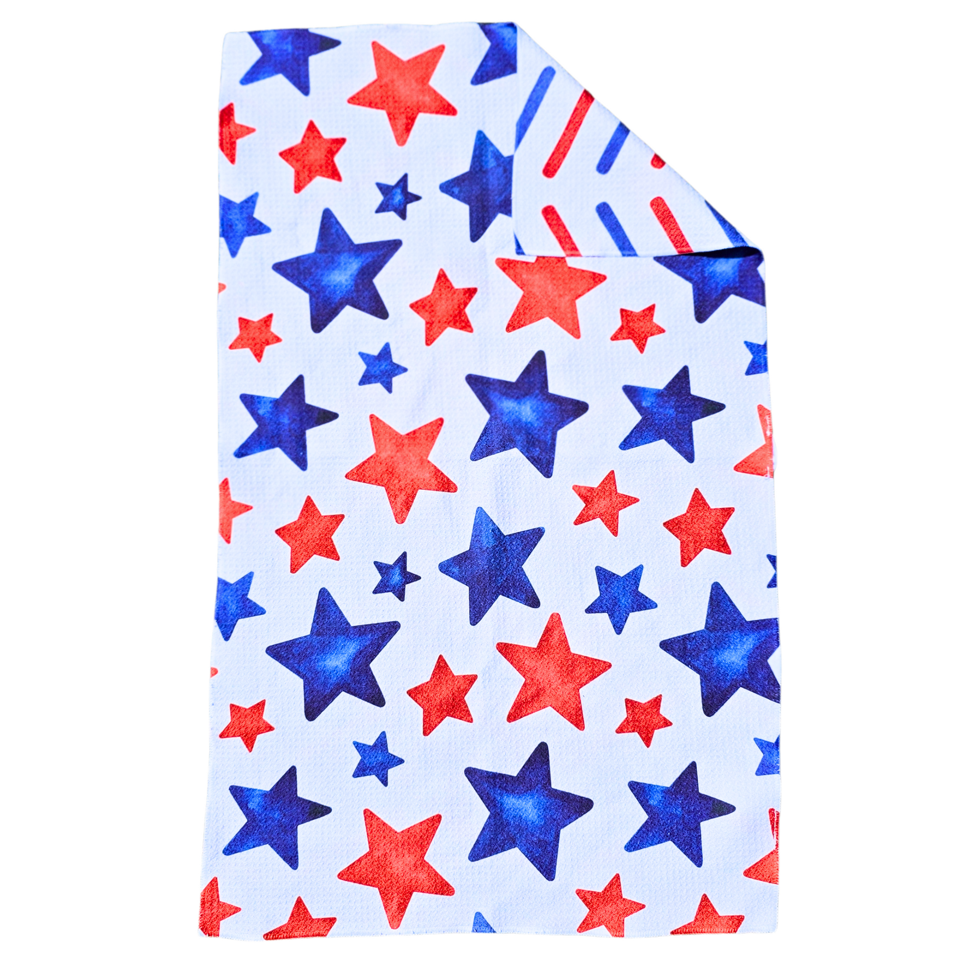 Double-sided waffle weave microfiber hand towel laid flat, featuring a white background with scattered red and blue stars in varying sizes, with a folded corner revealing the red and blue diagonal stripe reverse side.