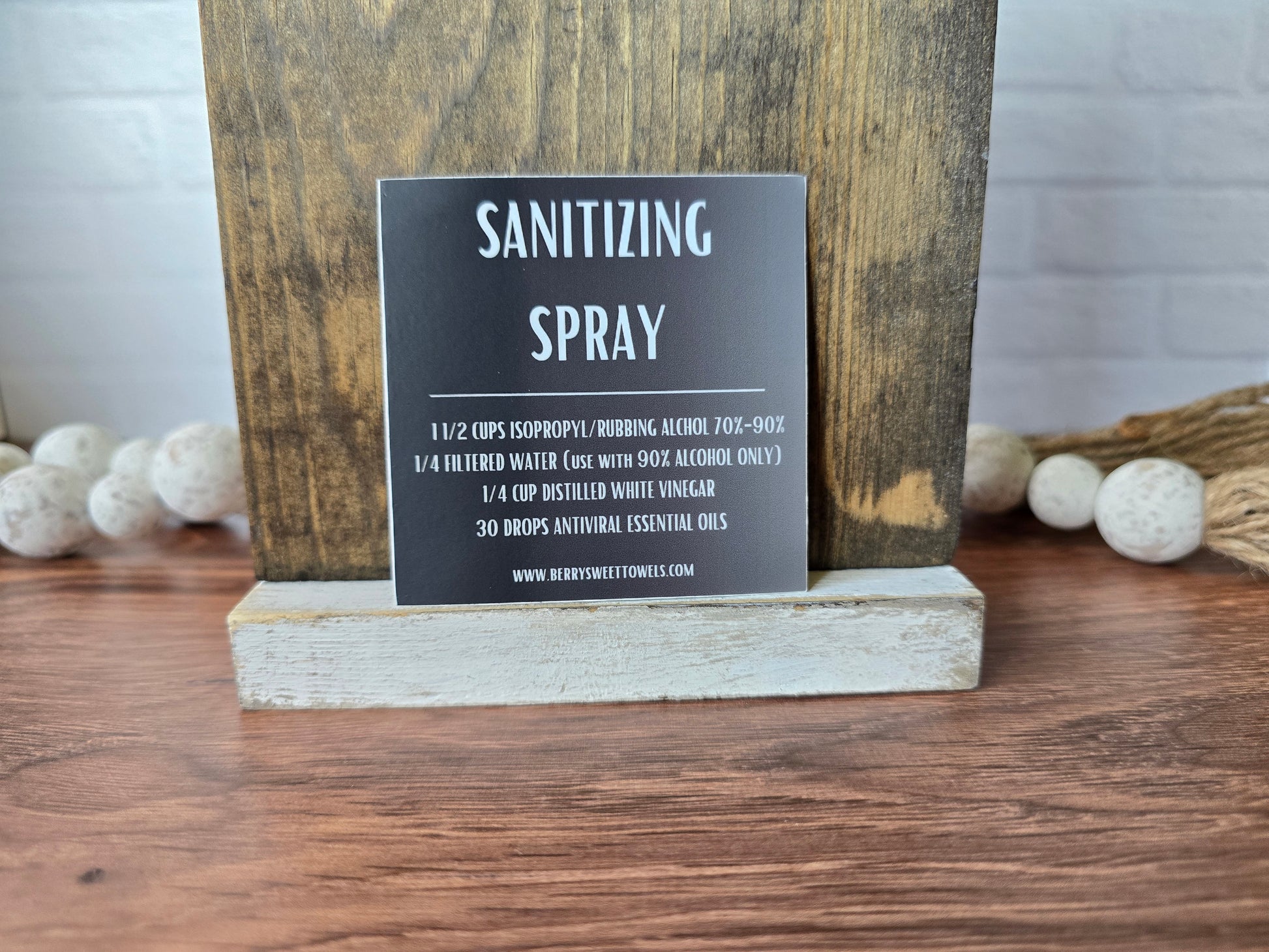 Square vinyl sticker with a black background and white text labeled “Sanitizing Spray,” displaying a DIY cleaning recipe using isopropyl alcohol, filtered water, distilled white vinegar, and essential oils.