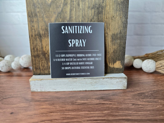 Square vinyl sticker with a black background and white text labeled “Sanitizing Spray,” displaying a DIY cleaning recipe using isopropyl alcohol, filtered water, distilled white vinegar, and essential oils.