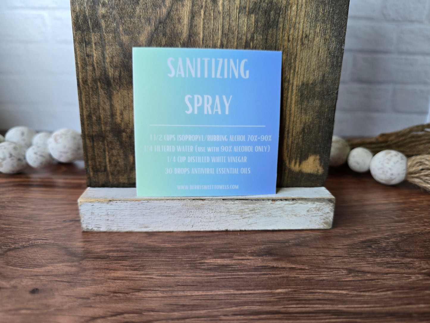 Square vinyl sticker with a green and blue background and white text labeled “Sanitizing Spray,” displaying a DIY cleaning recipe using isopropyl alcohol, filtered water, distilled white vinegar, and essential oils.