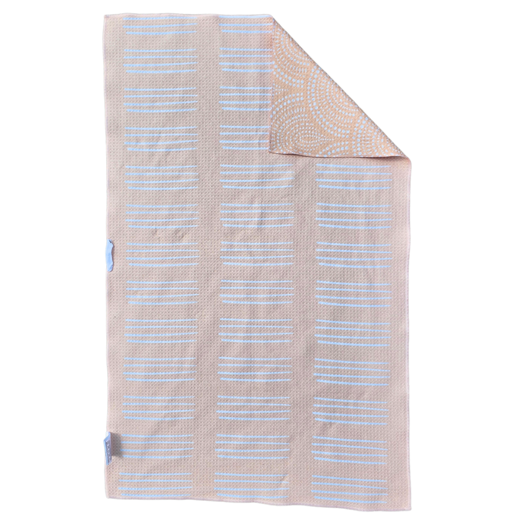 Soft yellow waffle weave microfiber hand towel laid flat with a folded corner, showing the reverse side with white linear stripe patterns and a partial view of the scalloped patterned front.