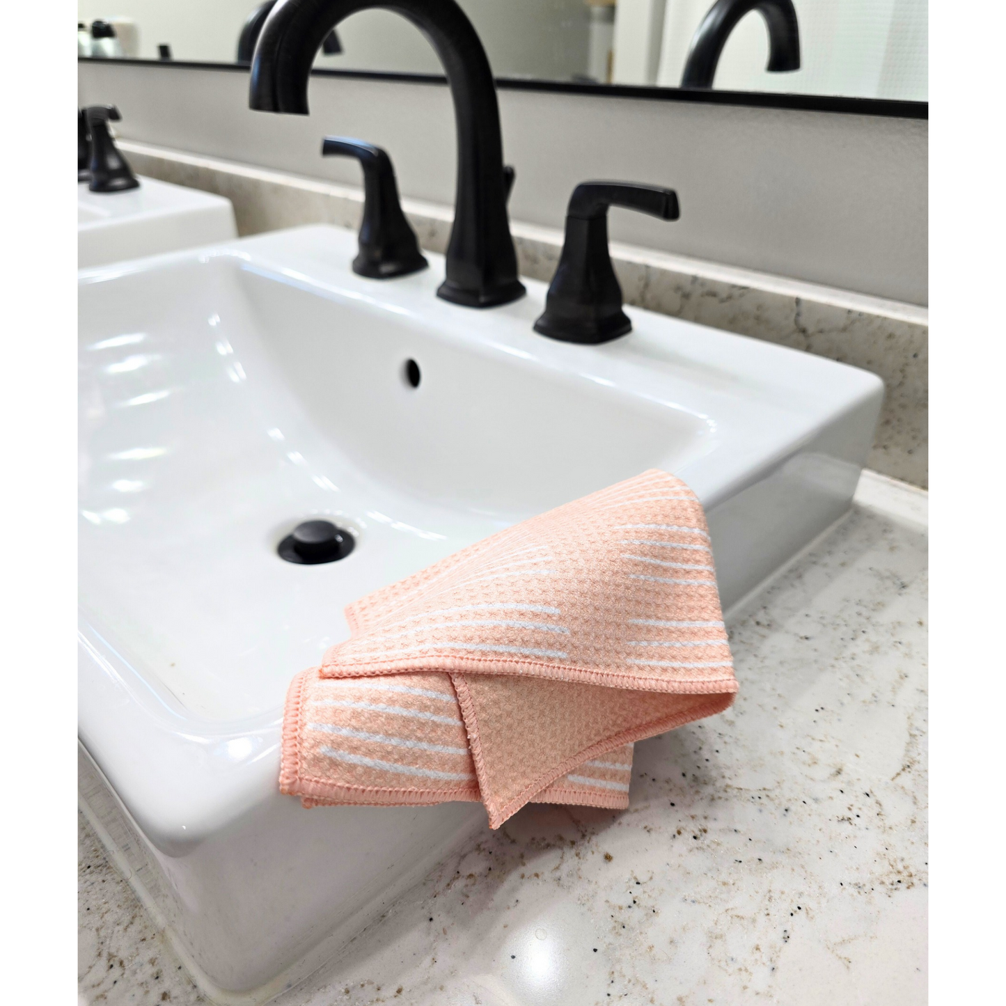 Soft-yellow waffle weave microfiber washcloth folded over the edge of a white bathroom sink, showing a white striped front pattern and solid yellow reverse side.
